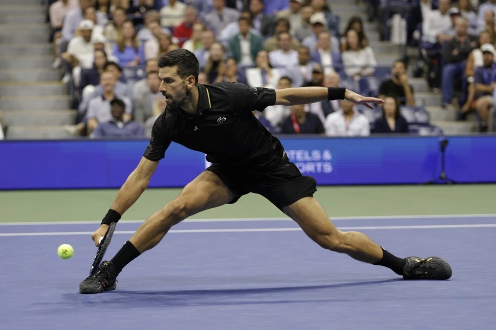Novak Djokovic lunging for a shot on an indoor tennis court