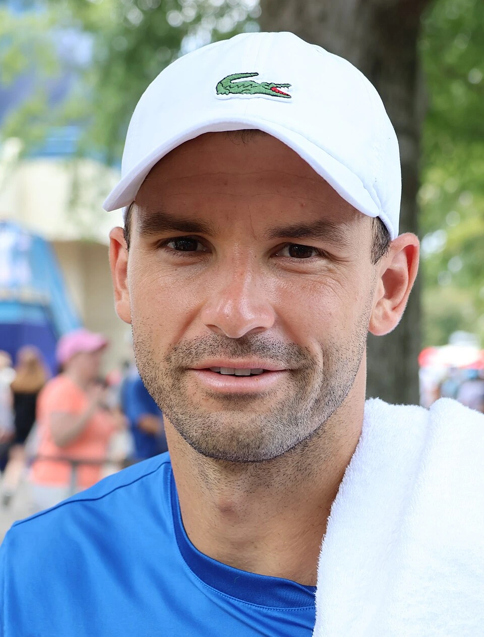 Grigor Dimitrov in a close-up tennis photo wearing a white cap and blue shirt